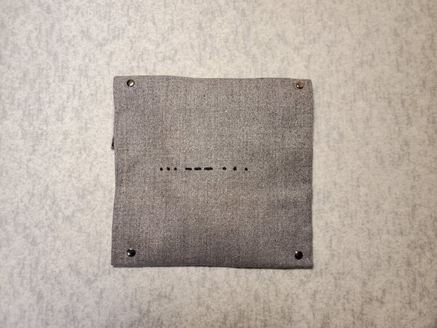 Grey cloth pouch, with the letters S, O, S written in Morse Code