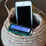 A phone rests inside a weaved basket, while a digital sensor displays the amount of time it sits within.