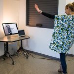 A woman is shown moving in front of a screen that is reflecting the movement back at her.