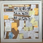 A corkboard displaying strange, awkward images of a white man, a black man, and a razer. Surrounding the images are sticky notes with questions surrounding racial bias in AI.