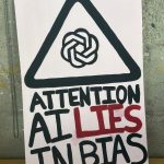 A poster features the phrase, "ATTENTION: AI LIES IN BIAS" with the word LIES written in red.