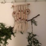 Strands of macrame knots hang together on a wall.