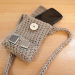 A phone rests inside a weaved pouch with two small digital displays attached.