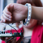 A woman is wearing the mindflUX band, which is connected via multiple wires.